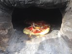 Lehmofen_klein15.jpg (197.17 KiB) 4966 mal betrachtet HURRA !!! Die erste Pizza (ok, das hier war schon die zweite ...) ist fertig!!<br />Deutlich schneller, als erwartet!<br />Vor lauter Übermut und Eifer ist die Pizza noch nicht ganz fertig getillert (d.h. der Teig ist nicht ganz gebacken), schmeckt aber mit mineralischer Ascheeinlage trotzdem hervorragend.<br />Es stellt sich heraus, dass die vorne liegenden Pizzen (da war das Feuer) deutlich fertiger sind, als die hinten im Brennraum liegenden.<br />Dennoch - diese ersten Pizzen sind auf jeden Fall als Erfolg zu verbuchen.